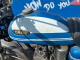 une moto bleue et blanche garée devant un panneau bleu
