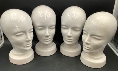quatre têtes de mannequins blanches sont alignées en rang