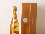 une photo montrant une bouteille de champagne posée à côté d'une boîte sur une table