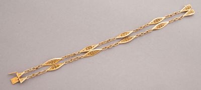 a gold bracelet with a long chain and a leaf design