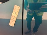 a man standing next to a car with a ruler on the side