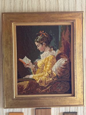un tableau représentant une femme en train de lire un livre, accroché au mur