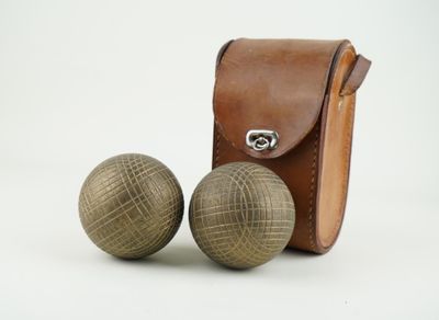 une paire de boules en bois avec un étui en cuir sur fond blanc