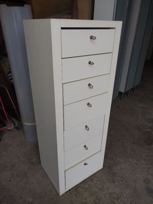 a tall white cabinet with five drawers in it