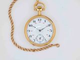 a gold pocket watch with a chain on a white surface
