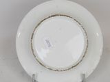 a white plate with a gold rim on a stand