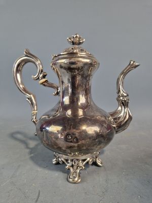 une théière ancienne en argent, munie d'une anse, posée sur une table