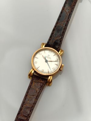 a close up of a watch on a white surface with a brown strap