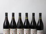 six bouteilles de vin sont alignées sur une table en bois