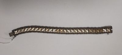un gros plan d'un bracelet argenté et noir posé sur une surface blanche