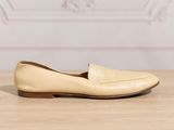 tan leather loafer shoes on a wooden table with a white wall in the background