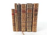 several old books are stacked on top of each other on a white surface