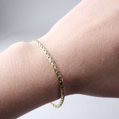 a gold chain bracelet on a woman ' s arm