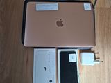 a pink apple laptop sitting on a wooden floor next to a charger and a charger