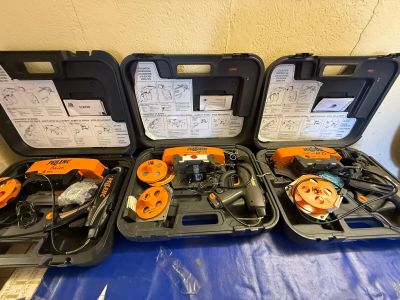 Trois outils noirs et orange sont posés dans un coffret sur une table bleue