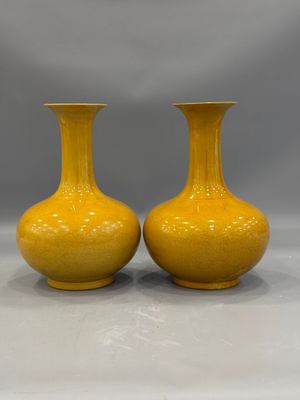 pair of yellow vases sitting on top of a white table