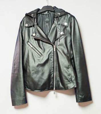 une veste en cuir noir suspendue à un cintre accroché au mur