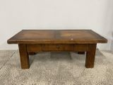 une vieille table basse en bois surmontée de deux tiroirs