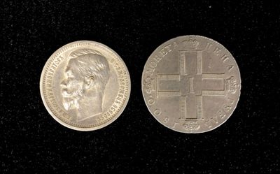 two silver coins with a cross on them on a black surface
