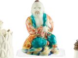 quatre figurines asiatiques différentes exposées sur un socle blanc