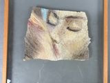 tableau représentant le visage d'une femme, dans un cadre en bois accroché au mur