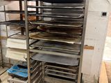 several trays of food are stacked on a metal rack in a kitchen