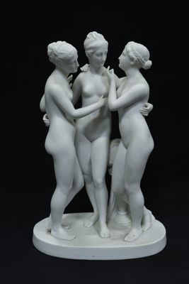 deux statues blanches représentant trois femmes se tenant par la main, posées sur un fond noir