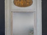 un miroir dans un coin d'une pièce où est accroché un tableau au mur