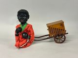 figurine of a black man in a red robe with a wooden cart