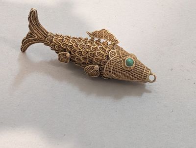 une broche en forme de poisson rouge sertie d'une pierre verte