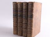 three old books are stacked on top of each other on a white surface