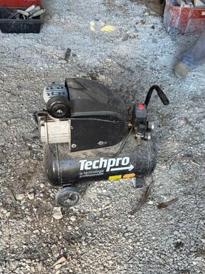un petit compresseur d'air posé par terre, dans la poussière