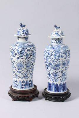pair of blue and white vases with lids on wooden bases