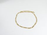 Le bracelet en chaîne d'or est posé sur une feuille de papier