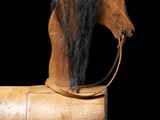 a wooden horse with a black mane on it ' s head