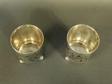 two silver cups that are sitting on a table