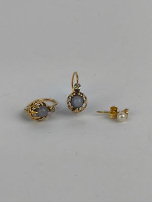 a pair of earrings and a pearl earring on a white surface