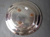 a silver plate with four brown dots on it on a table