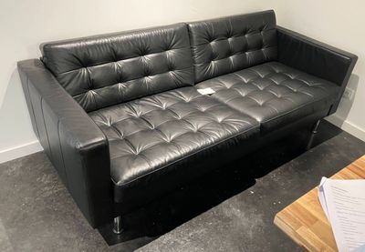 a black leather couch sitting in a corner of a room