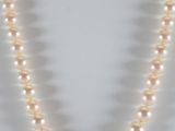 a white pearl necklace with a gold clasp on a white background