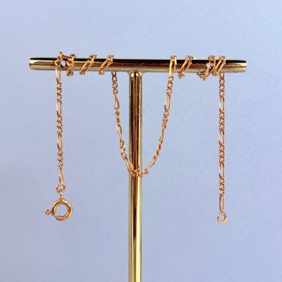 un collier en or posé sur un support, avec des chaînes qui en pendent
