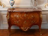 a marble topped chest of drawers with a vase on top