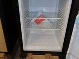 a small black refrigerator with its door open in a room