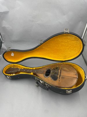 une guitare dans son étui, posée sur une surface blanche