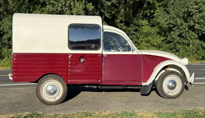 un petit camion rouge et blanc garé sur le bord de la route