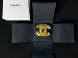 a close up of a black bow tie with a gold chanel pin