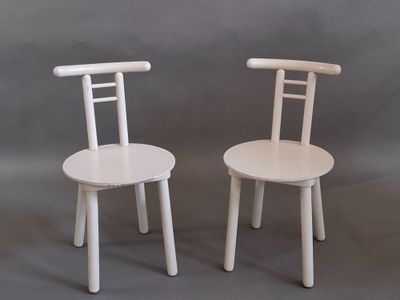 two white chairs sitting next to each other on a gray background