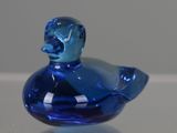 a blue glass duck sitting on top of a table