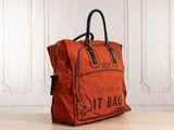 an orange bag sitting on top of a wooden floor next to a white wall