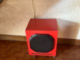 une enceinte rouge posée par terre devant un lit